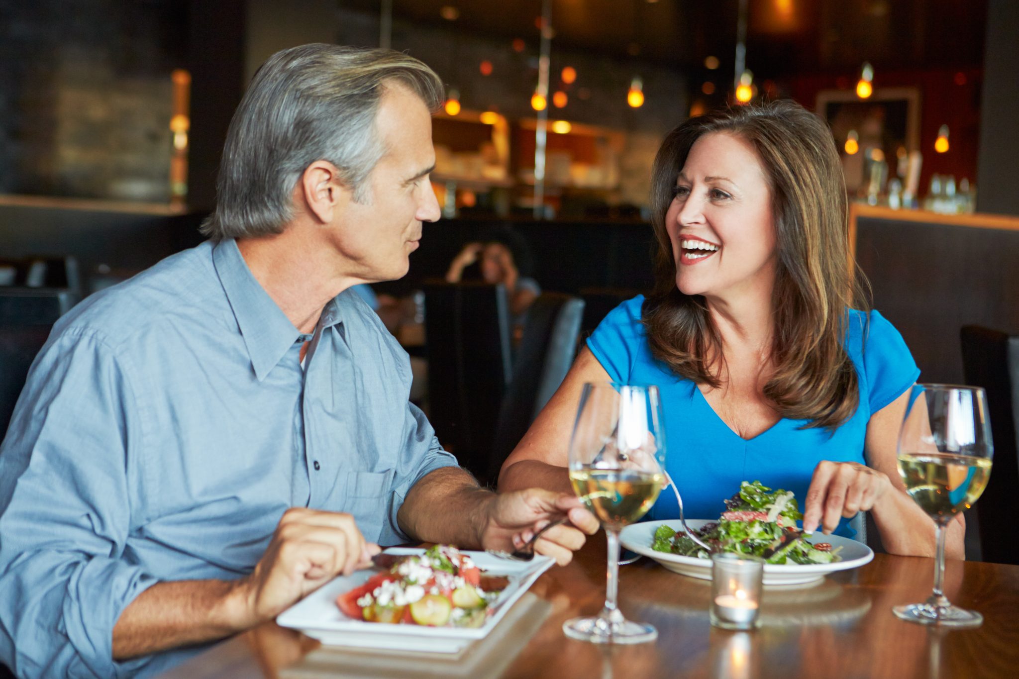 Mature couple dining at a restaurant, representing caregivers and seniors enjoying time together and saving through senior discounts in the DMV area.
