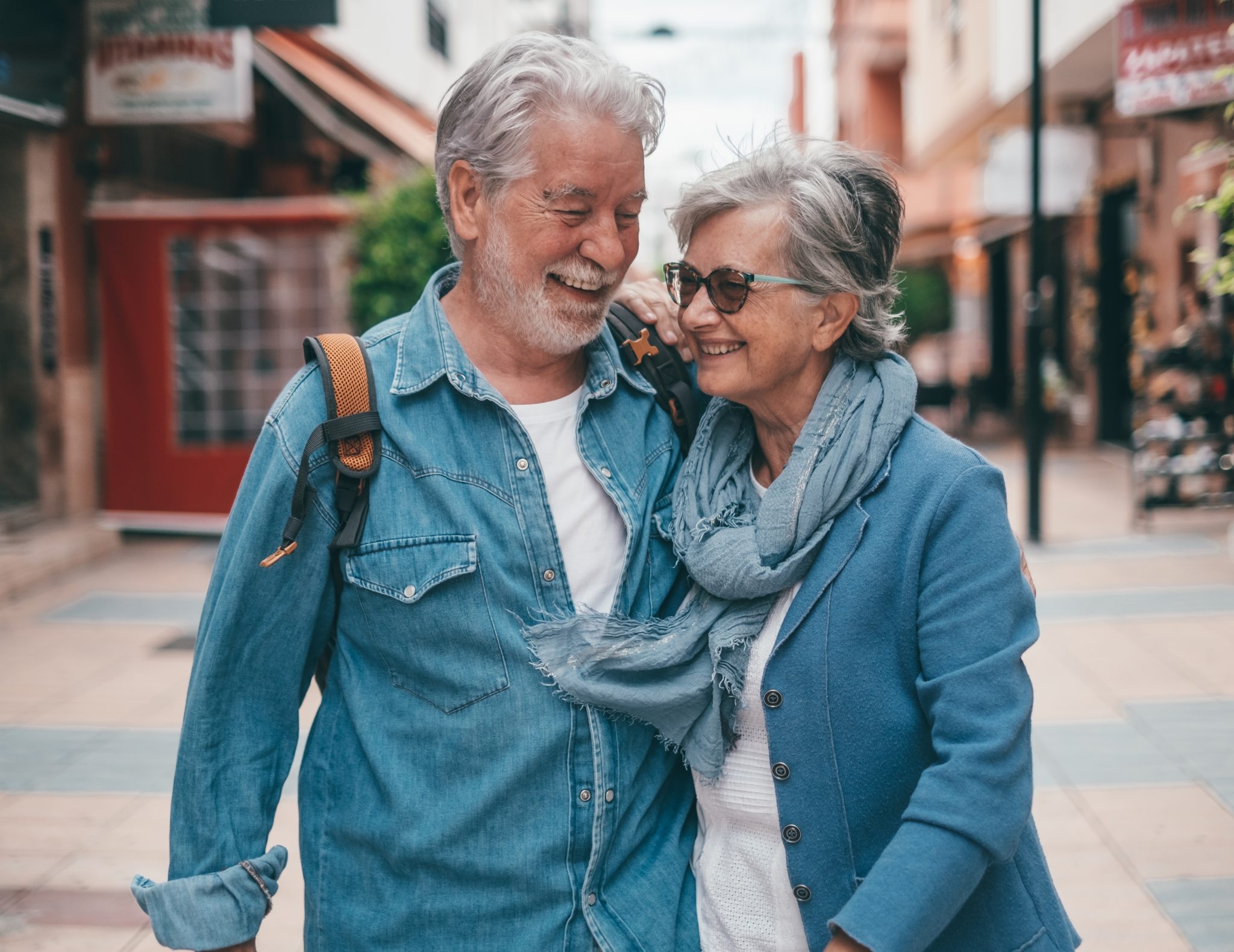 Older couple walking together on a city street, smiling and talking